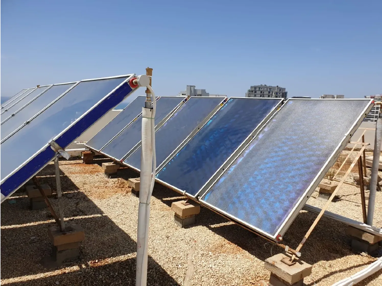 מערך קולטי שמש שטוחים על גג בניין מגורים, מערכת סולארית מרכזית לחימום מים של מקור הטבע