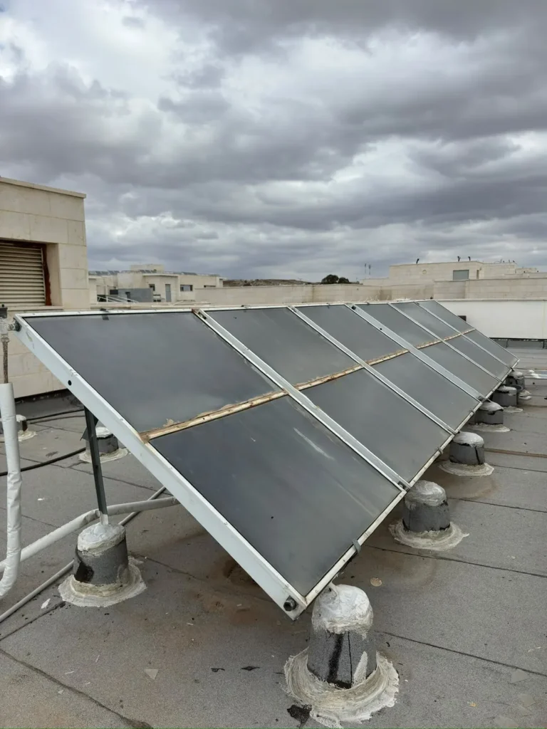 קולטי שמש לחימום מים על גג בניין — צילום מעבודות מקור הטבע